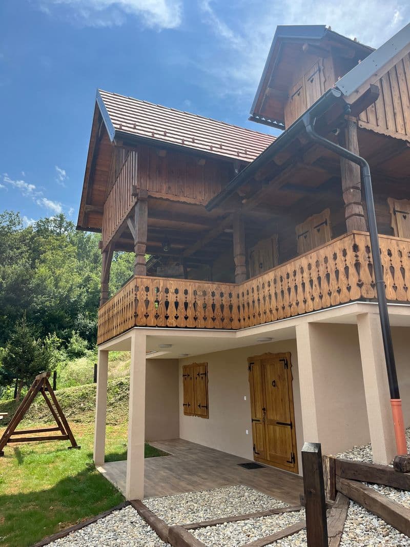 Side view of the oak house with a wooden A-frame swing in the garden