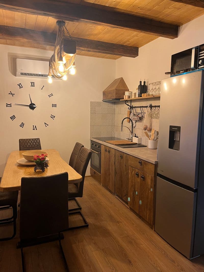 Fully equipped kitchen and wooden dining table with a large wall clock