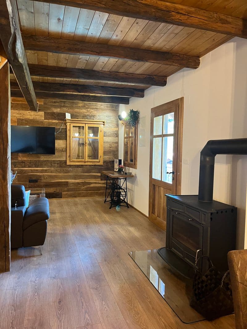 Cosy living room with reclaimed wood walls, wood-burning stove and TV