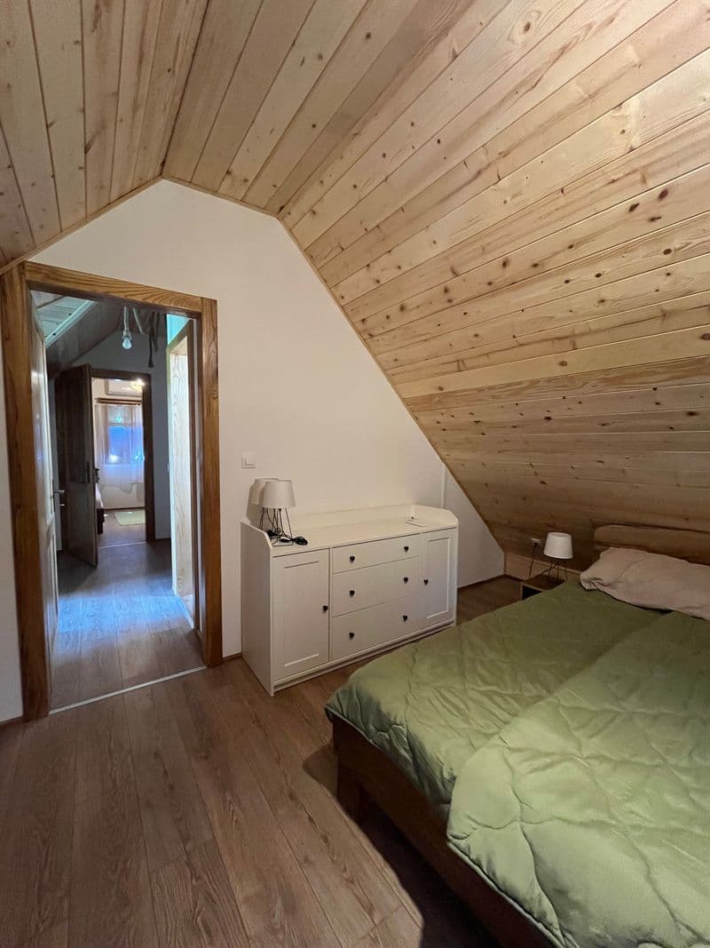 Attic bedroom with a double bed, timber ceiling and soft green linens