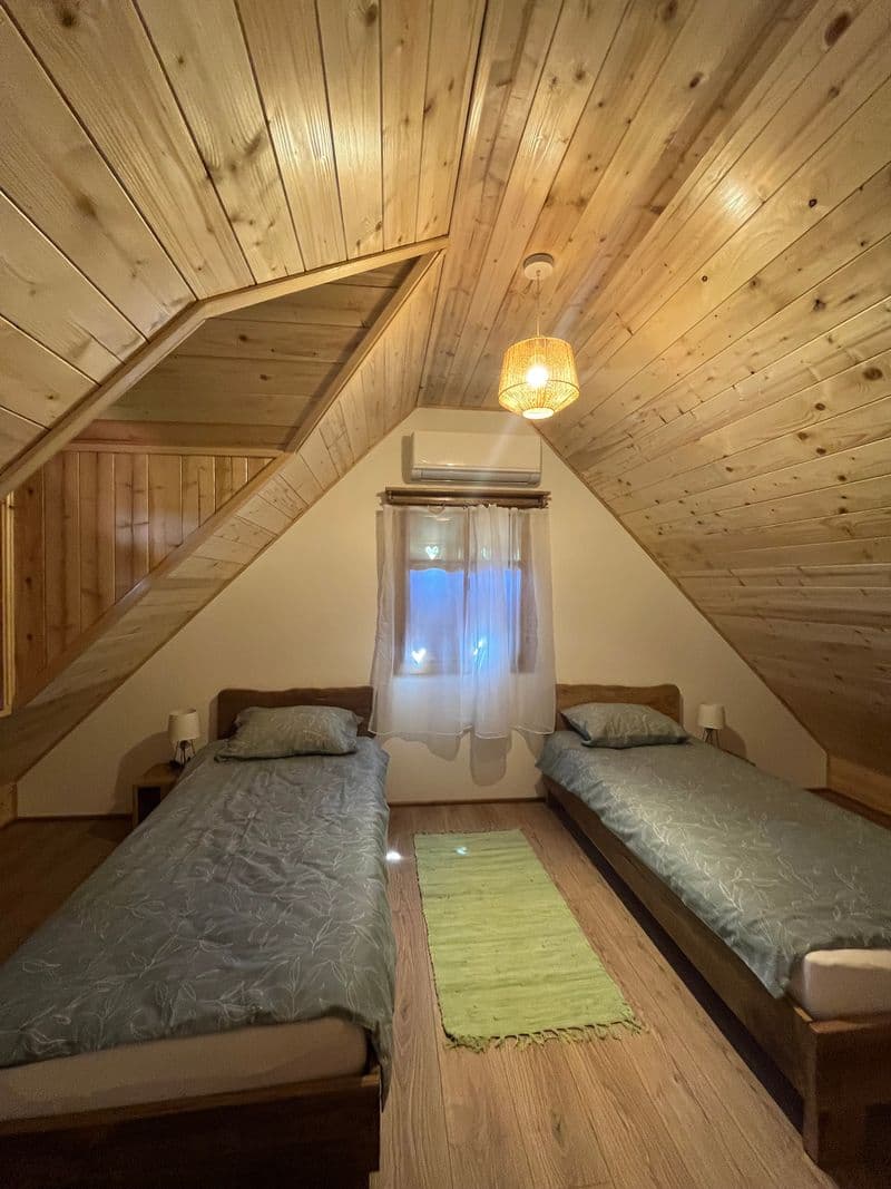 Twin bedroom at night with warm pendant lighting and wooden ceiling