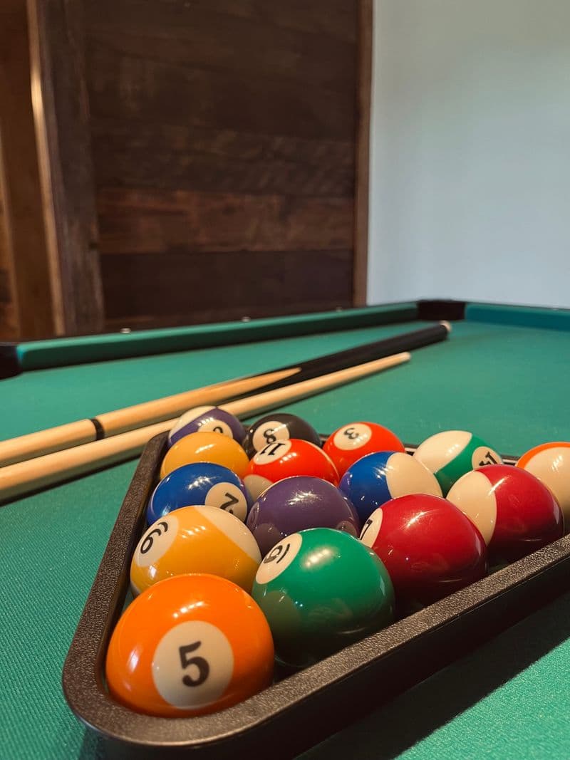 Close-up of racked pool balls and cues on the green felt table